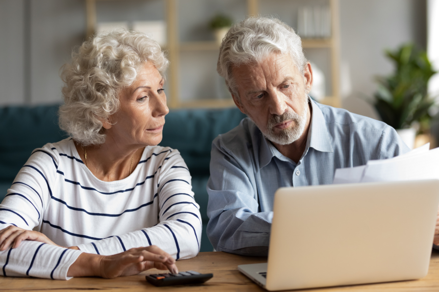 Older couple reviewing documentation and on a computer.